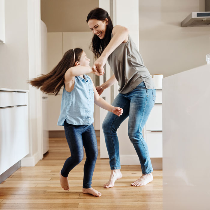 mom and young daughter dancing in the kitchen