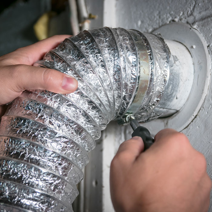 man connecting dryer vent to wall
