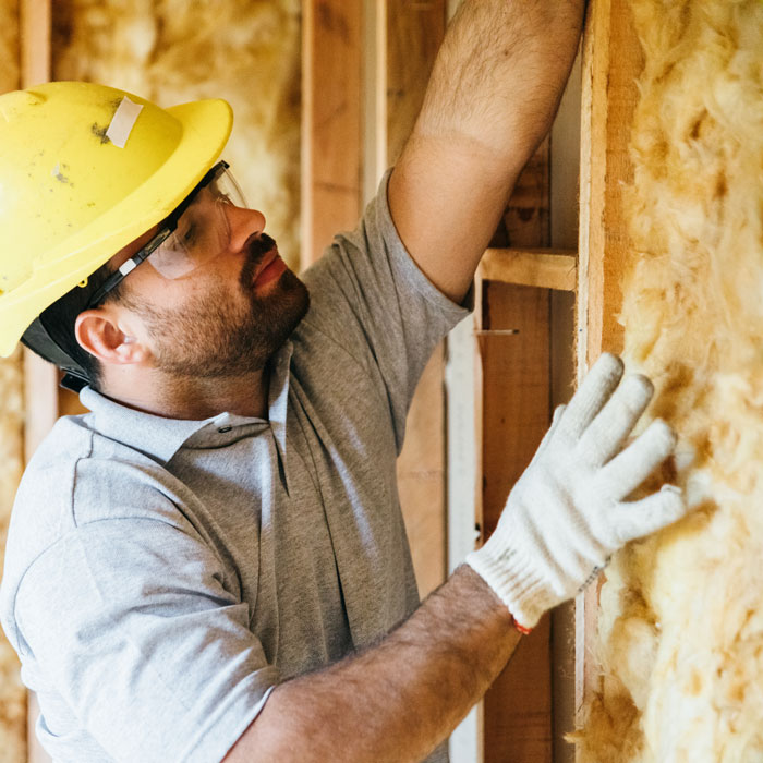 man placing insulation into walls